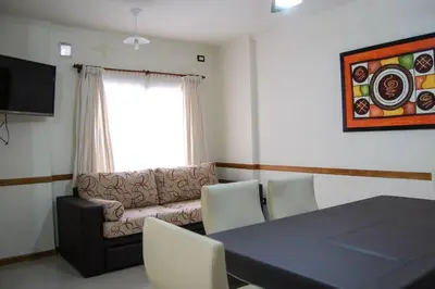 a living room with a couch and a table and chairs at Departamento, Terraza con PISCINA, SUM y PARRILLAS a 2 cuadras de PEATONAL in Villa Carlos Paz
