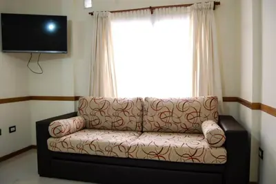 a living room with a couch in front of a window at Departamento, Terraza con PISCINA, SUM y PARRILLAS a 2 cuadras de PEATONAL in Villa Carlos Paz