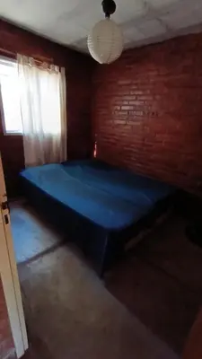 a blue bed in a room with a brick wall at Al Pie Del Cerro Champaqui in Los Hornillos