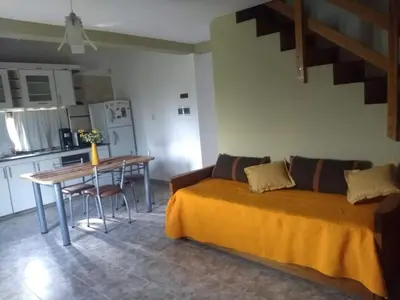a room with a bed and a table and a kitchen at AMALGAMA CABAÑAS in Merlo