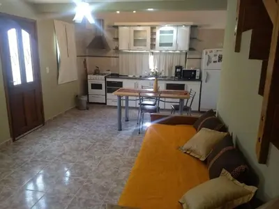 a living room with a couch and a table in a kitchen at AMALGAMA CABAÑAS in Merlo