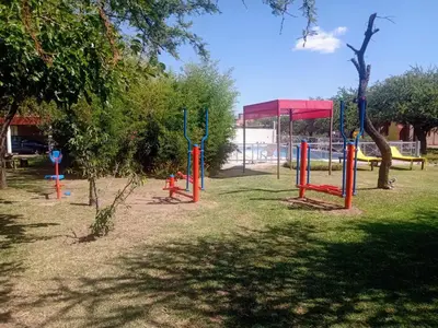 a park with playground equipment in the grass at AMALGAMA CABAÑAS in Merlo