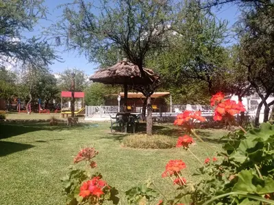 a picnic shelter in a park with red flowers at AMALGAMA CABAÑAS in Merlo