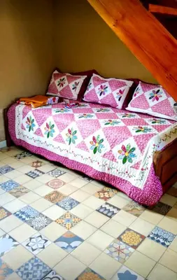 a bed with a quilt on top of a tiled floor at Los Laureles de Sorso in Villa Ciudad Parque