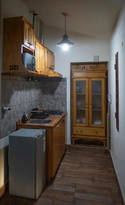 a kitchen with wooden cabinets and a sink and a refrigerator at La Chuklla, alojamiento cerca al lago in Almafuerte