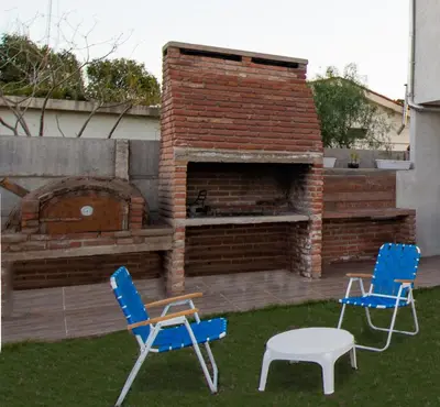 two blue chairs and a table and a brick oven at La Chuklla, alojamiento cerca al lago in Almafuerte