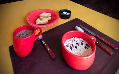 two red cups of coffee on a table with food at La Chuklla, alojamiento cerca al lago in Almafuerte