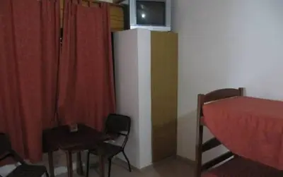 a room with a refrigerator and a bed and a table at Posada A Lo De Santys in Villa Independencia
