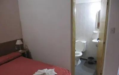 a small bathroom with a bed and a toilet at Posada A Lo De Santys in Villa Independencia