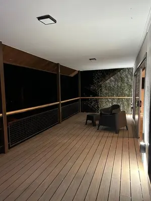 a balcony with a couch and a chair on a wooden floor at La cumbrecita ,Casitas super lujo in La Cumbrecita