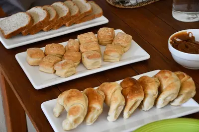 a table with three plates of pastries and bread at Altos de Brochero Cabañas & Padel in Villa Cura Brochero