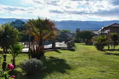 a yard with palm trees and a wooden fence at Altos de Brochero Cabañas & Padel in Villa Cura Brochero