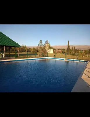 a large blue swimming pool with a green roof at Las Masias de Nono in Nono