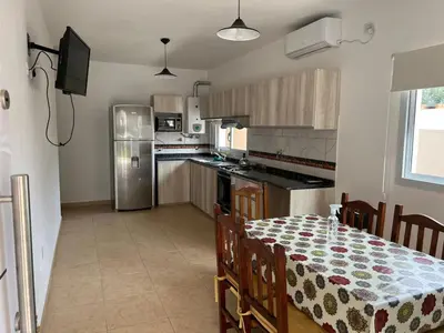 a kitchen with a table and a kitchen with a refrigerator at La Nonita in Villa Carlos Paz