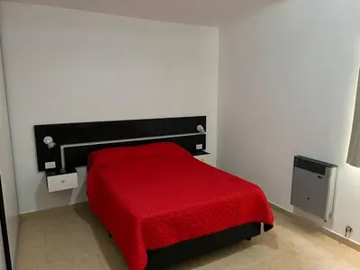 a bedroom with a red bed with a red blanket at La Nonita in Villa Carlos Paz