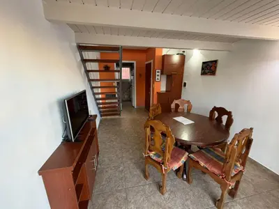 a dining room with a table and chairs and a television at Costalago in Villa Carlos Paz