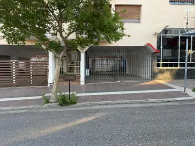 a building with a tree on the side of the street at Costalago in Villa Carlos Paz