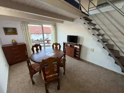 a dining room with a table and chairs and a staircase at Costalago in Villa Carlos Paz