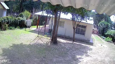 a tree with a swing in front of a house at Cabaña wawa in Villa Ciudad Parque