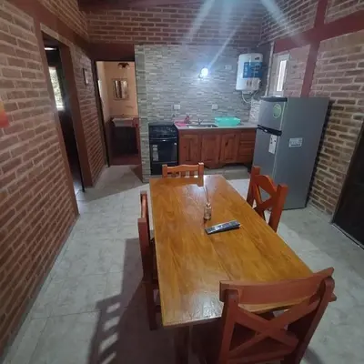 a kitchen with a wooden table with chairs and a refrigerator at Cabañas Juan in Arroyo de Los Patos