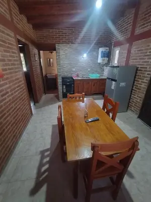 a kitchen with a wooden table with chairs and a stove at Cabañas Juan in Arroyo de Los Patos