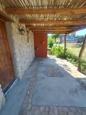 a patio with a stone wall and a wooden pergola at Cabañas Juan in Arroyo de Los Patos