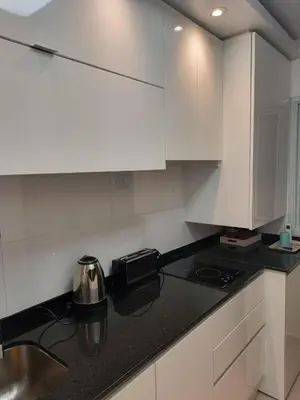 a kitchen with white cabinets and a black counter top at Depto carlos paz in Villa Carlos Paz