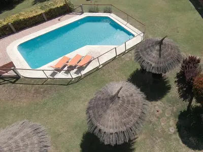 an overhead view of a swimming pool with two large umbrellas at Las Magnolias - Casas de Campo in Mina Clavero
