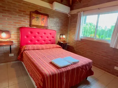 a bedroom with a red bed with two towels on it at Las Magnolias - Casas de Campo in Mina Clavero
