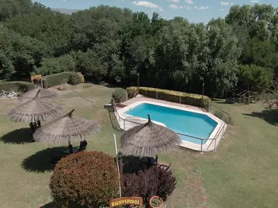 a swimming pool in a yard with umbrellas at Las Magnolias - Casas de Campo in Mina Clavero