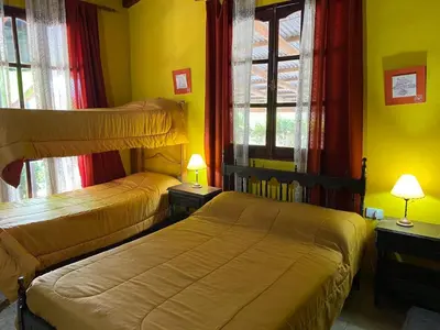 two beds in a room with yellow walls and windows at Paseo por las Nubes in Santa Rosa de Calamuchita