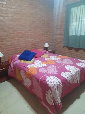 a bed with a colorful comforter in a bedroom at Cabañas Lo De Elias in San Lorenzo