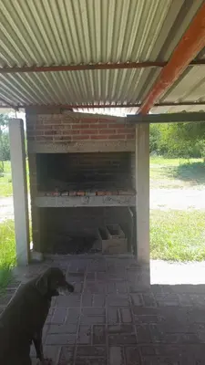 a dog standing in front of an outdoor oven at Cabañas Lo De Elias in San Lorenzo