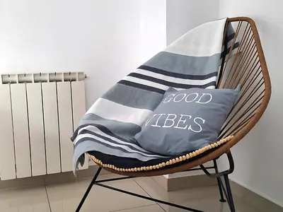 a wicker chair with a blue and white blanket on it at Disfruta Córdoba en un departamento premium! in Cordoba
