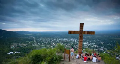 a group of people sitting around a wooden cross on a hill at Casa Abuela Tere in Santa Rosa de Calamuchita