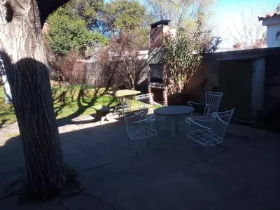 a patio with a table and chairs next to a tree at Casa Abuela Tere in Santa Rosa de Calamuchita