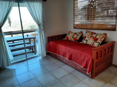 a bedroom with a bed with red sheets and a window at Ventura 2 in Estancia Vieja