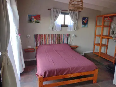 a bedroom with a bed with a purple blanket at El Colibrí de los Molles in Los Molles