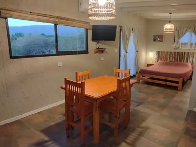 a dining room with a table and chairs and a bed at El Colibrí de los Molles in Los Molles