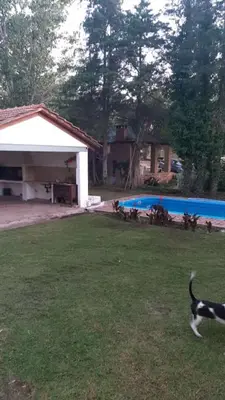 a dog running in a yard next to a swimming pool at CASA FRENTE AL RIO CON PILETA PRIVADA ESTANCIA VIEJA Carlos Paz in Villa Carlos Paz
