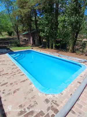 a swimming pool with blue water in a yard at CASA FRENTE AL RIO CON PILETA PRIVADA ESTANCIA VIEJA Carlos Paz in Villa Carlos Paz