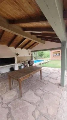 a wooden bench sitting under a roof on a patio at CASA FRENTE AL RIO CON PILETA PRIVADA ESTANCIA VIEJA Carlos Paz in Villa Carlos Paz