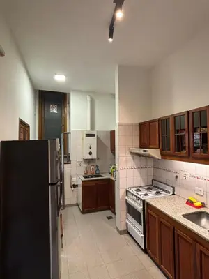 a kitchen with a black refrigerator and wooden cabinets at Casa en Nueva Córdoba con Patio y Asador in Cordoba