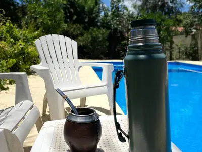 a green thermos sitting on a table next to a pool at La Cantata in Merlo