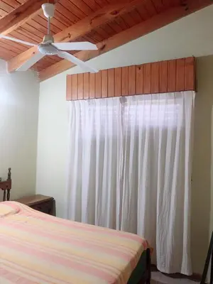 a bedroom with a bed and a white curtain at Merlindo Alojamiento in El Rincón