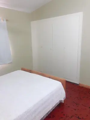 a bedroom with a white bed and white cabinets at Merlindo Alojamiento in El Rincón