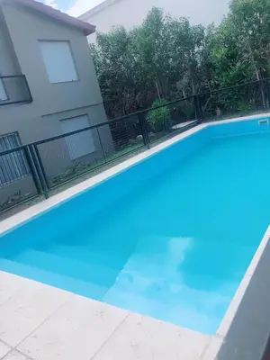 a blue swimming pool in front of a house at Merlindo Alojamiento in El Rincón