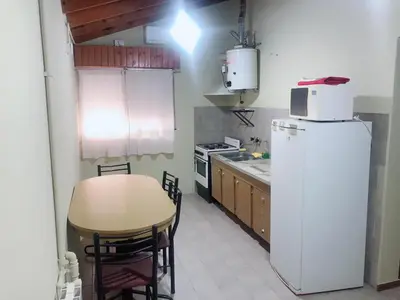 a kitchen with a table and a white refrigerator at Merlindo Alojamiento in El Rincón