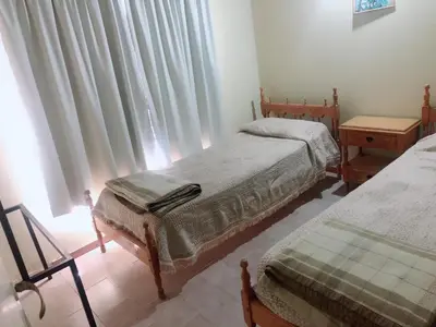 a bedroom with two beds and a window with curtains at Merlindo Alojamiento in El Rincón