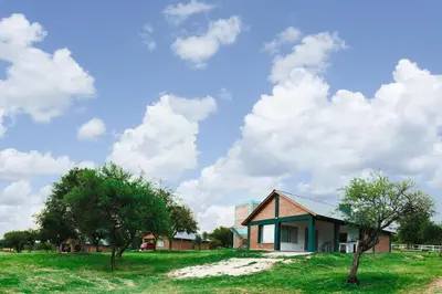 a small house in a field with two trees at Cabañas El Principio in Villa Cura Brochero